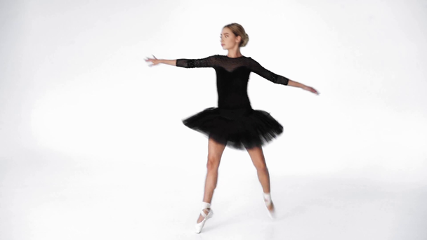 Χαριτωμένη μπαλαρίνα εκτελεί κλασικές χορευτικές κινήσεις σε λευκό φόντο - Πλάνα, βίντεο