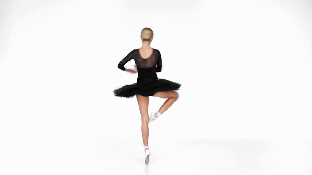 Bailarina joven en falda de ballet negro bailando en punta sobre fondo blanco - Imágenes, Vídeo
