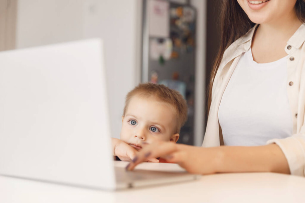 ビジネスのお母さんは彼女の男の子の赤ん坊の家との時間を使うオンライン仕事のラップトップ、女性を使用している - 写真・画像