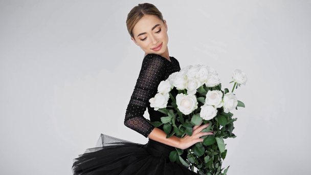 Elegante ballerina met boeket rozen op camera op witte achtergrond - Video
