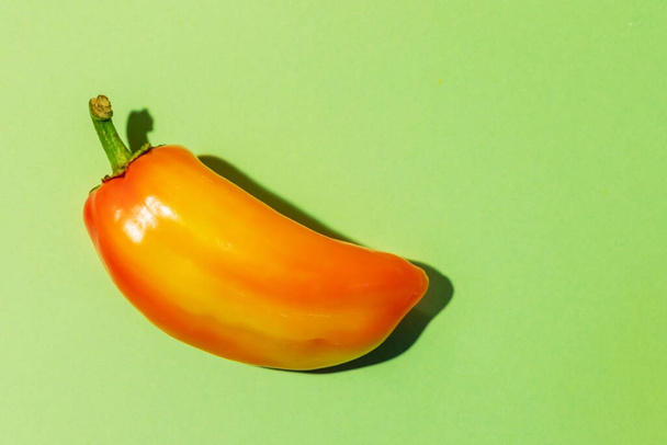 Δείτε πάνω από ώριμο ζουμερό πορτοκαλί πιπέρι σε πράσινο φόντο με χώρο αντιγραφής. Διαφήμιση υγιή φυσικά τρόφιμα. Φθινόπωρο φόντο. Έννοια εποχής συγκομιδής λαχανικών. - Φωτογραφία, εικόνα