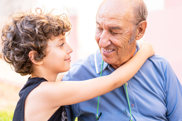 Großvater und Enkel verliebt. Enkelkind sieht seinem Opa in die Augen und umarmt sich. Familienkonzept. - Foto, Bild