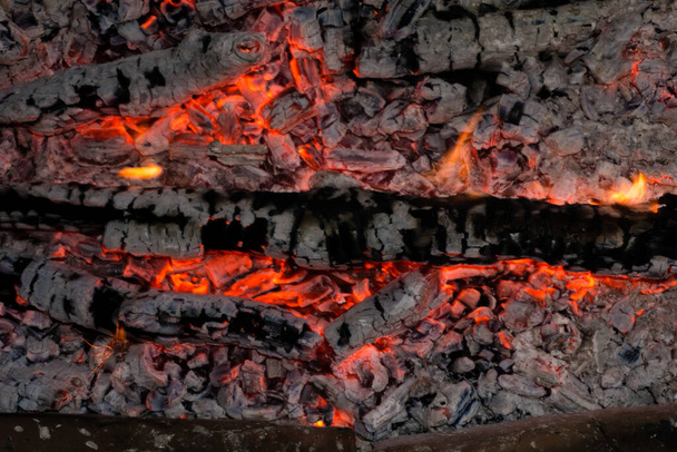 Smeltende sintels van vuur, levende kolen, brandende houtskool op de achtergrond textuur, close-up, gloeiende kolen - Foto, afbeelding