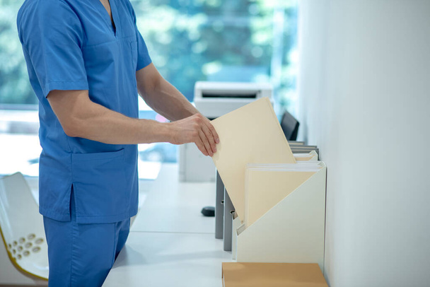 Trabajador médico en traje azul con documento - Foto, Imagen