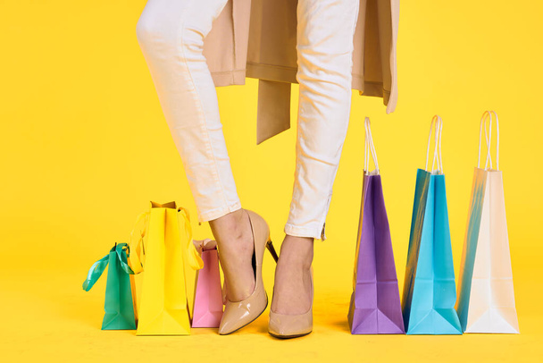 pieds féminins dans les sacs de chaussures shopping style de vie jaune fond isolé - Photo, image