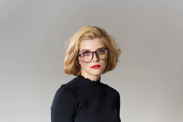 Blonde fille avec des lunettes lèvres rouges chemisier noir vue recadrée glamour lumière arrière-plan studio - Photo, image