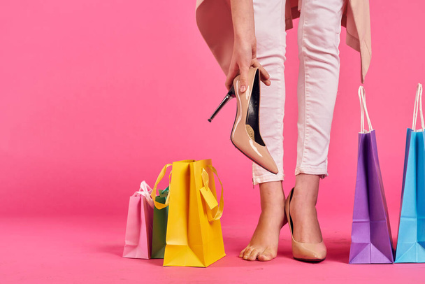 Alışveriş torbaları ayakkabılı kadın ayakları Alışveriş kolik pembe arka plan - Fotoğraf, Görsel