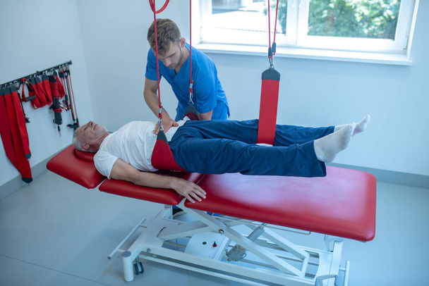 Male doctor and patient at physio procedure - Фото, изображение