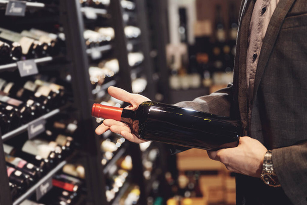 Cantinero sommelier toma botella de vino tinto del mostrador de la tienda de bebidas restaurante - Foto, imagen