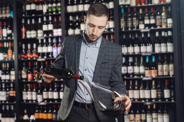 Сомелье наливает красное вино в графин, чтобы сделать аэрационный напиток - Фото, изображение