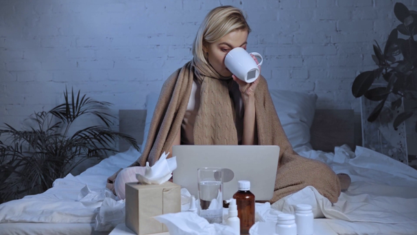 beteg szabadúszó használja laptop közelében gyógyszert és italok a hálószobában  - Felvétel, videó