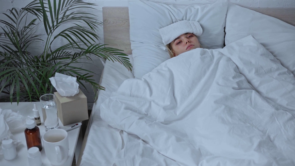 korkea kulma näkymä sairas nainen pyyhe otsassa makaa lähellä lääkitystä  - Materiaali, video