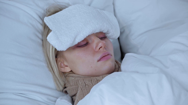 mujer enferma con toalla en la frente acostada en el dormitorio  - Imágenes, Vídeo