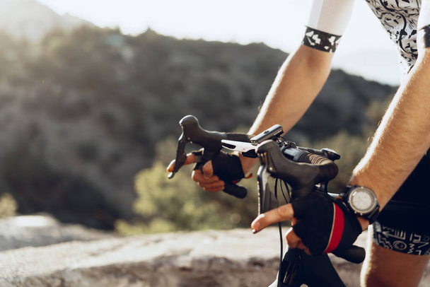 Hands of a professional cyclist in gloves on handle bar of a bicycle - Fotoğraf, Görsel