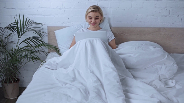 junge blonde Freiberuflerin benutzt Laptop im Schlafzimmer  - Filmmaterial, Video