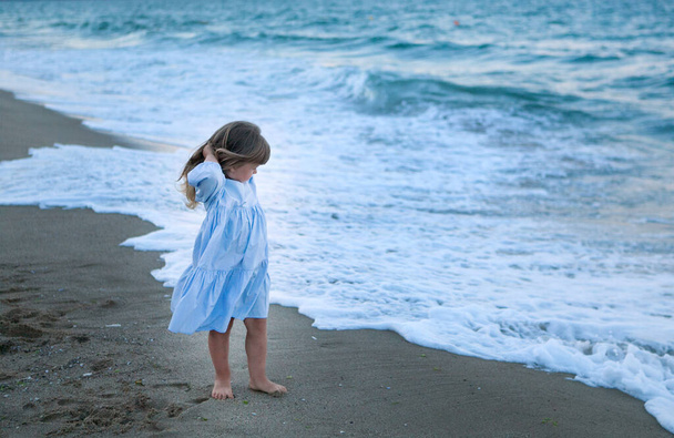 cute girl on the seashore at sunset in a blue dress - Foto, Imagem