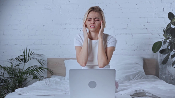 sick freelancer touching head while having migraine near laptop  - Footage, Video