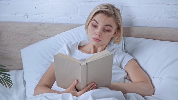 blond en jong vrouw lezen boek in slaapkamer - Video