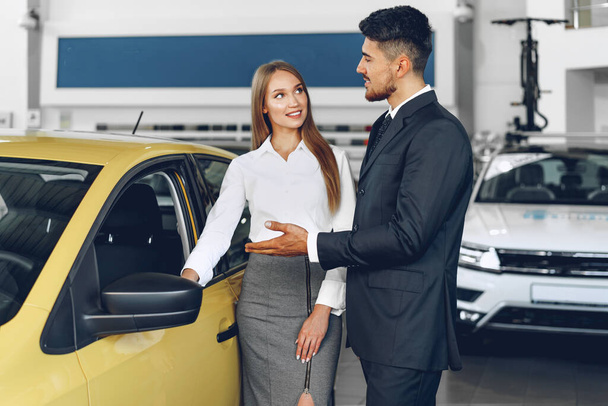 Man car dealer showing a woman buyer a new car - Fotografie, Obrázek