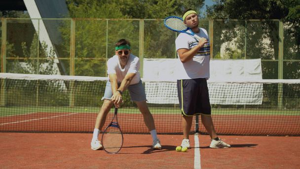 Тенісні гравці позують біля сітки на корті
 - Фото, зображення