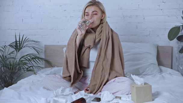 zieke vrouw neemt pil in de buurt smartphone met blanco scherm en servetten op bed - Video