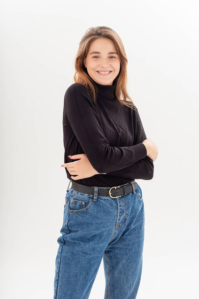 young caucasian woman in turtleneck and blue jeans isolated on white background - Фото, изображение