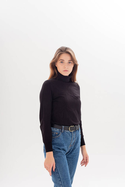 young caucasian woman in turtleneck and blue jeans isolated on white background - Foto, imagen