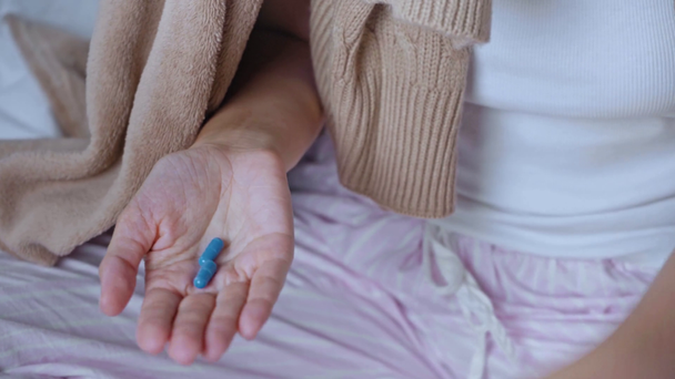 καλλιεργημένη άποψη της άρρωστης γυναίκας που κρατά μπουκάλι με μπλε κάψουλες  - Πλάνα, βίντεο