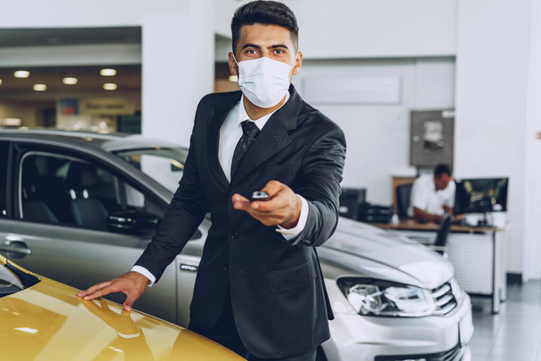 Man car dealer wearing protective medical mask on his working place - Фото, изображение