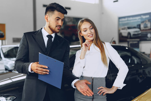 Man car dealer showing a woman buyer a new car - Foto, Bild