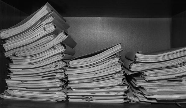 Paper documents stacked in archive. Documents on the shelves of archive room. Office shelves in the closet full of files. black and white photo - Photo, Image