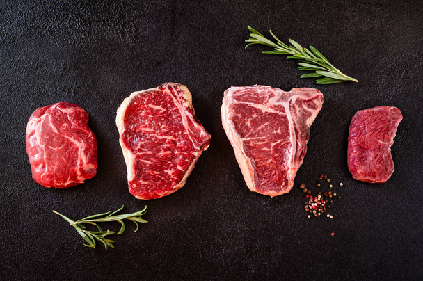 Variety of beef steaks on dark background - Фото, изображение