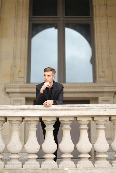Joven chico guapo apoyado en la barandilla de hormigón balcón en París. - Foto, imagen