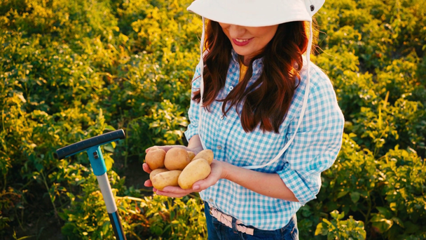 vista de ángulo alto de la mujer en el sombrero con patatas frescas en las manos  - Imágenes, Vídeo
