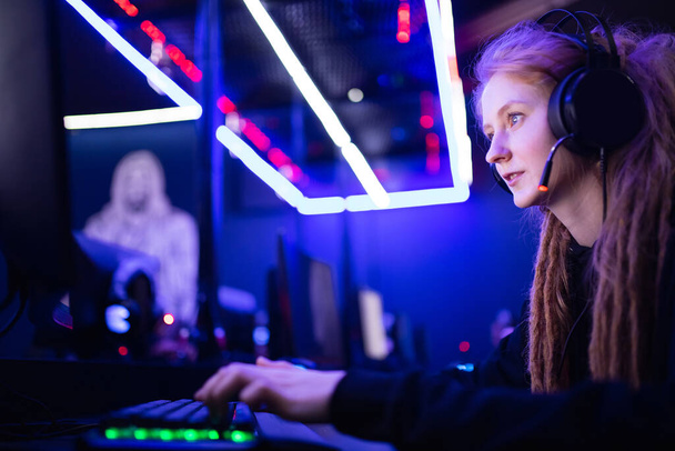 Streamer gyönyörű lány professzionális játékos mosoly játék online játékok számítógép fejhallgató, neon szín - Fotó, kép
