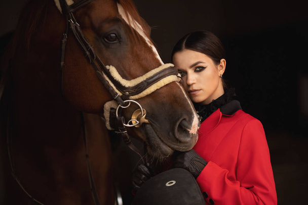 Mulher jockey cavaleiro abraça cavalo marrom com os olhos fechados. Conceito amor animais - Foto, Imagem