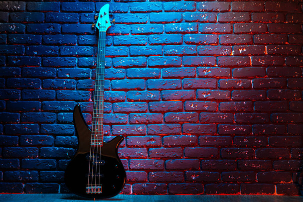 Electric guitar in neon light against dark walll - Foto, imagen