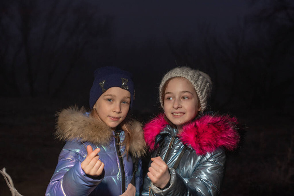 二人の女の子が笑っている。幸せよ。彼らは手で心を示します。冬のジャケットを着た2人の女の子が手で心を見せる。若いです女の子で冬ショー心とともに彼らの手. - 写真・画像