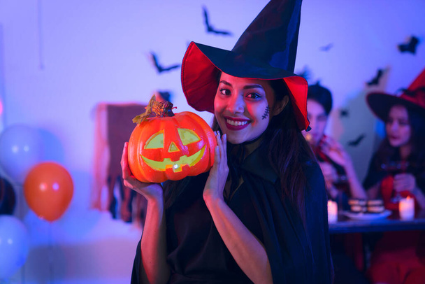 gelukkig jonge vrouwen in zwart heks halloween kostuums op feest met pompoen en cocktails met schorpioenen hebben funover vleermuis witte achtergrond - Foto, afbeelding