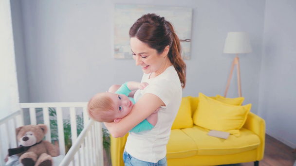 ブルネット母看護赤ん坊男の子近くクリブ  - 映像、動画