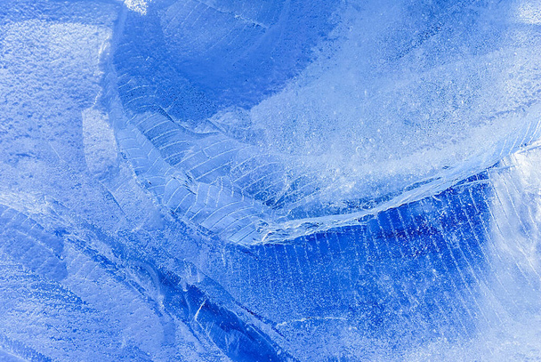 Ice cubes on white glass mirror background with reflection isolated close  up, a lot of blue transparent frozen crushed ice cubes, clear spilled water  drops, cold freshness drink ingredient, copy space Stock