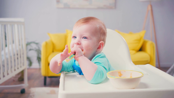 csecsemő gyerek szopás kanál bébiétel közelében tál az asztalon  - Felvétel, videó