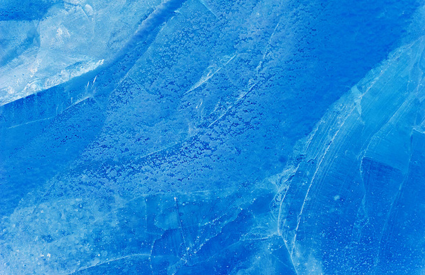 blauw ijs textuur met een patroon en scheuren achtergrond, ijs bevroren ijsbaan winter achtergrond, textuur van ijs oppervlak voor ontwerpers, blokken bevroren water - Foto, afbeelding