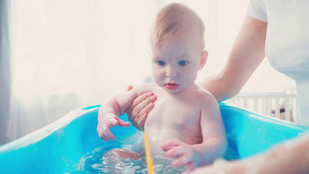 Äiti koskettaa pikkulapsi poika leikkii lelu kylvyssä - Materiaali, video