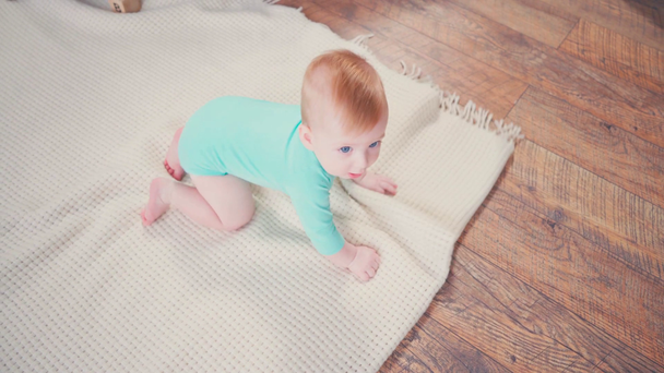 Ansicht von oben: Säugling kriecht auf Decke und blickt in Kamera - Filmmaterial, Video