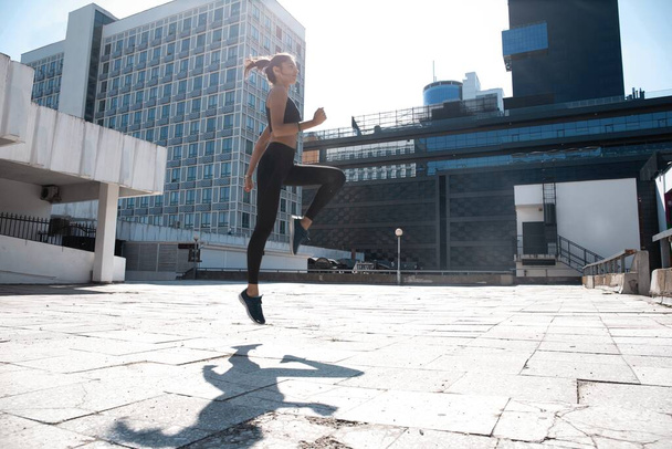 Slim brunette woman wears sports clothes jumping during her fitness workout. - Fotoğraf, Görsel