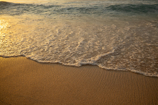 Landschaftlich reizvolle Meereslandschaft. Milchige Schaumwellen am Sandstrand. Sonnenuntergang. Wasserlandschaft als Hintergrund. Ausgewählte Soft Art-Schwerpunkte. Reflexion des Sonnenlichts auf dem Wasser und nassem Sand. Balangan Strand, Bali, Indonesien - Foto, Bild