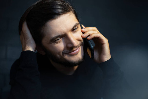 Nahaufnahme Porträt eines lächelnden jungen Mannes, der mit dem Smartphone spricht.  - Foto, Bild
