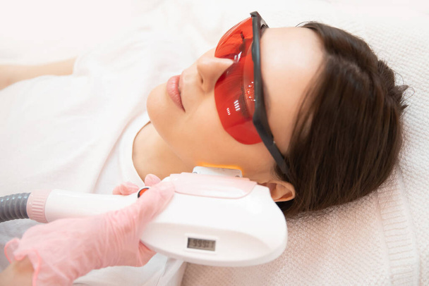 Master carries out removal of unwanted hair laser on face young woman. Health and beauty concept - Fotoğraf, Görsel