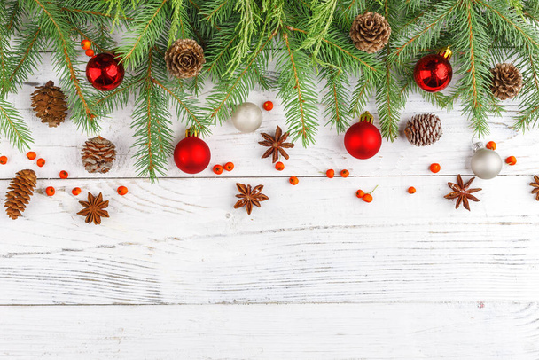 Kompozycja bożonarodzeniowa z ramą gałązek jodłowych, dekoracjami świątecznymi i szyszkami sosnowymi. Płaskie ułożenie, widok z góry - Zdjęcie, obraz